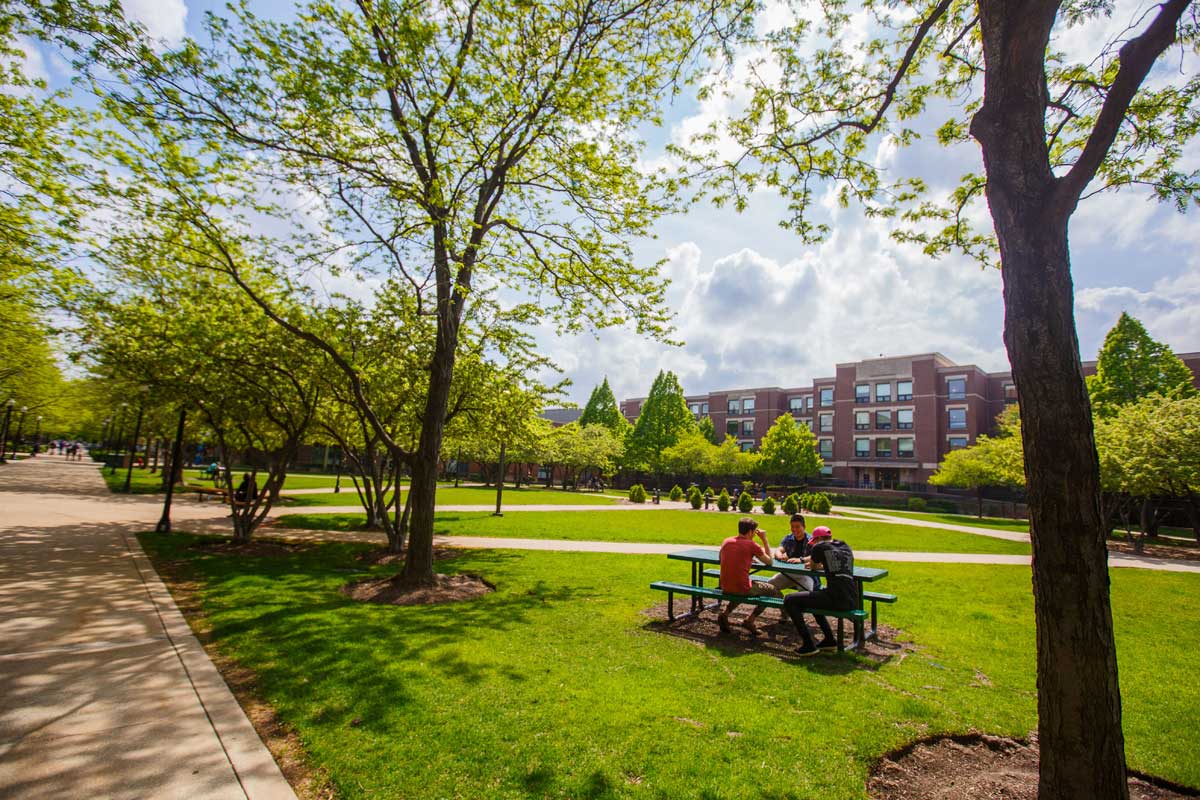 Students sitting at a picnic bench on the Lincoln Park campus